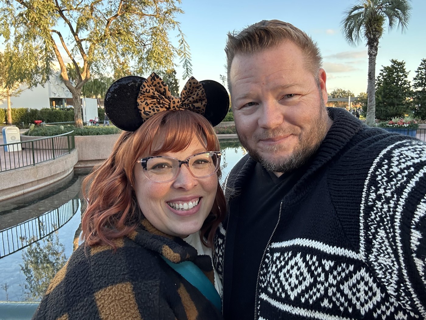 Ken and Manda smiling together at EPCOT, with Spaceship Earth in the background